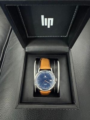 une montre dans une boîte noire posée sur un siège en cuir noir