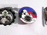 trois insignes sur un fond blanc ; l'un comporte une horloge et l'autre une image