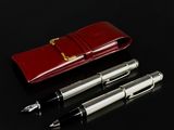 two pens and a red case on a black surface