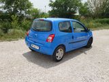 a small blue car parked in a gravel lot