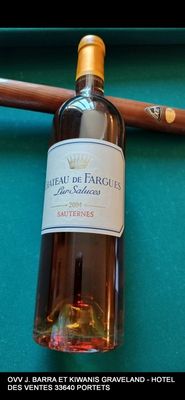 une bouteille de vin posée sur une table de billard, à côté d'une queue de billard