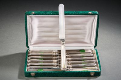 un service d'argenterie dans un coffret vert posé sur une table