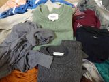 une pile de pulls et de pulls posée sur un lit
