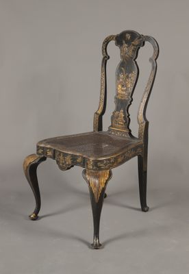 une chaise ancienne noire et dorée sur fond gris