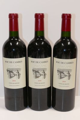 trois bouteilles de vin rouge sont alignées sur une surface blanche