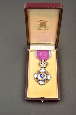 une photo d'une médaille violette et dorée dans un coffret en bois