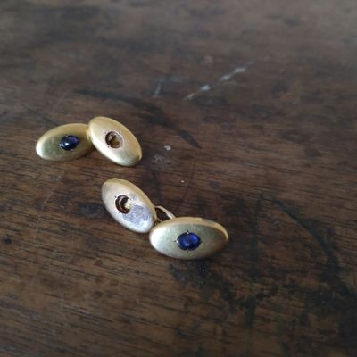 une paire de boucles d'oreilles en or et pierres bleues posées sur une table en bois