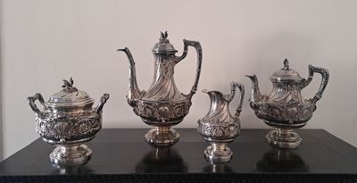 cinq théières en argent posées sur une table noire