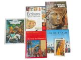 several books on a white surface with a statue of a woman