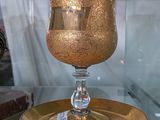 une table en verre sur laquelle se trouvent une assiette dorée et un verre