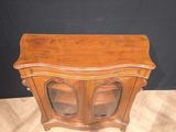 a small wooden cabinet with glass doors on top of it