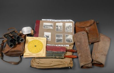 an assortment of old items including a pair of binoculars, a book, and a pair of leather boots