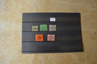une feuille de papier noir sur laquelle sont apposés des timbres de différentes couleurs