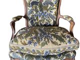 an old chair with a floral upholstered back and arms