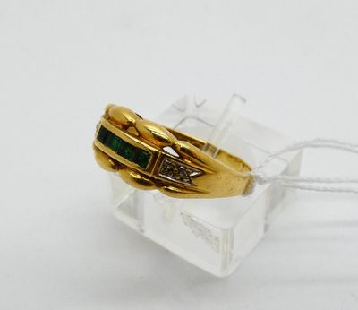 yellow gold ring with emerald and diamonds on a clear acrylic block