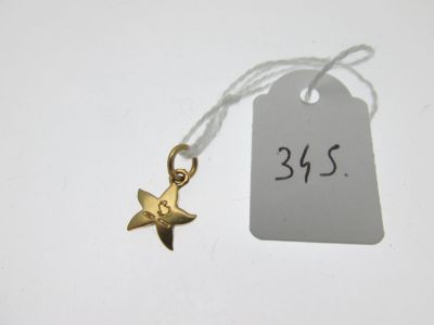 un petit pendentif en forme d'étoile en or sur lequel est accrochée une étiquette de prix