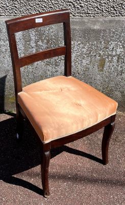 a wooden chair that has a tan seat on it