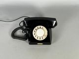 a black telephone sitting on a table with a white background