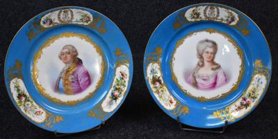 une paire d'assiettes bleues et dorées représentant le portrait d'une femme et d'un homme