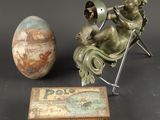 une statue représentant un enfant assis sur une chaise à côté d'un œuf