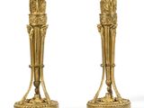 pair of antique brass candlesticks on pedestals on a white background