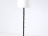 le lampadaire est muni d'un abat-jour blanc et d'un pied noir