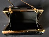 an image of a black and gold purse on a black background