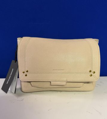 un sac à main blanc posé sur une table, avec un mur bleu en arrière-plan