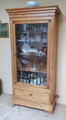 une armoire en bois avec une porte vitrée dans un salon