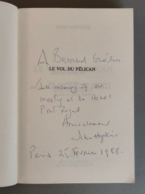 un livre ouvert, sur lequel est inscrit un poème manuscrit, posé sur une table