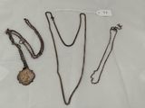 three necklaces and a key are on a white surface