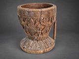 an old wooden vase with carvings on it sitting on a table