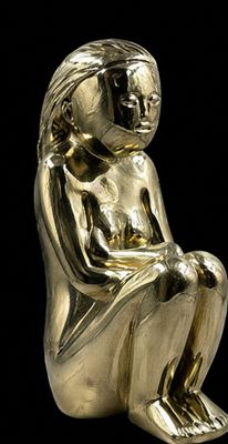 a gold figurine of a woman sitting on a black background