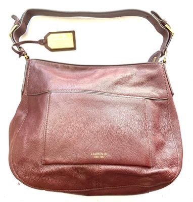 the brown leather purse is sitting on a white surface