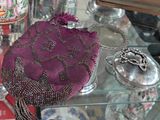 un sac à main violet posé sur une table en verre, à côté d'autres objets