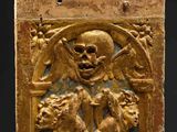 a gold plaque with a skull and a dog on it