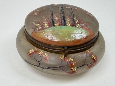 une boîte ronde ornée d'une peinture, posée sur une table