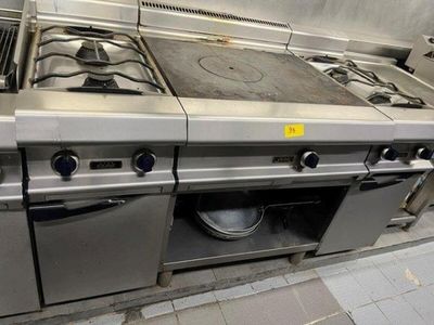 several stainless steel stoves in a commercial kitchen with pots and pans