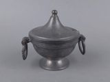 an old silver metal bowl with a handle and a lid