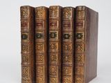 un ensemble de quatre livres anciens reliés en cuir sur fond blanc