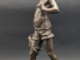 bronze statue of a boy on a rock with a hat on