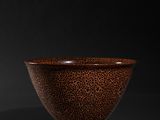 a brown and black bowl sitting on top of a black surface