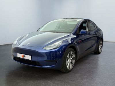 the blue tesla model y is parked in a white room