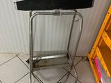 un tabouret en métal et une étagère dans un coin de la pièce