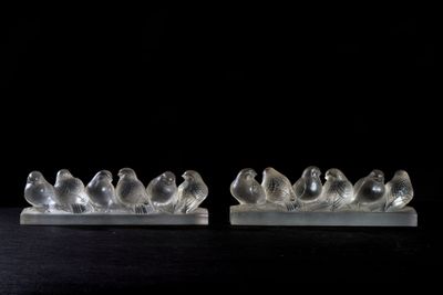 pair of clear glass birds sitting on a marble base