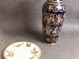 a blue and gold vase next to a small plate