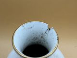 a white vase with a gold rim sitting on a table