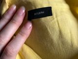 someone is holding a yellow shirt with a black label on it