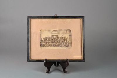 une vieille photo montrant un groupe d'hommes en uniforme devant un fond gris
