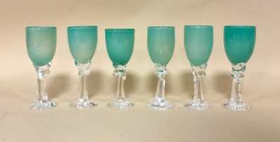 six verres à vin verts alignés en rang sur une table